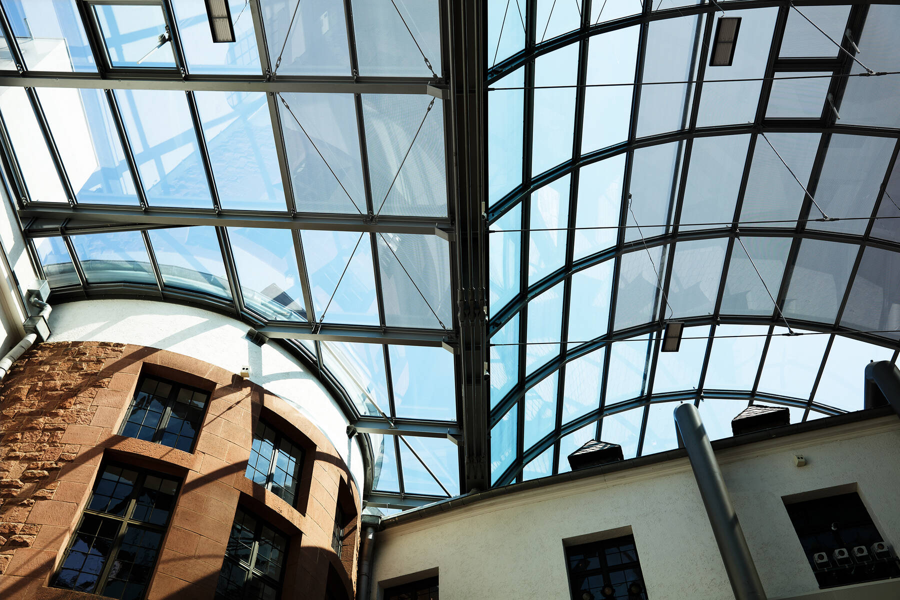 Upward view into the steel and glass construction of the museum roof, spanning the large courtyard without any supporting columns.