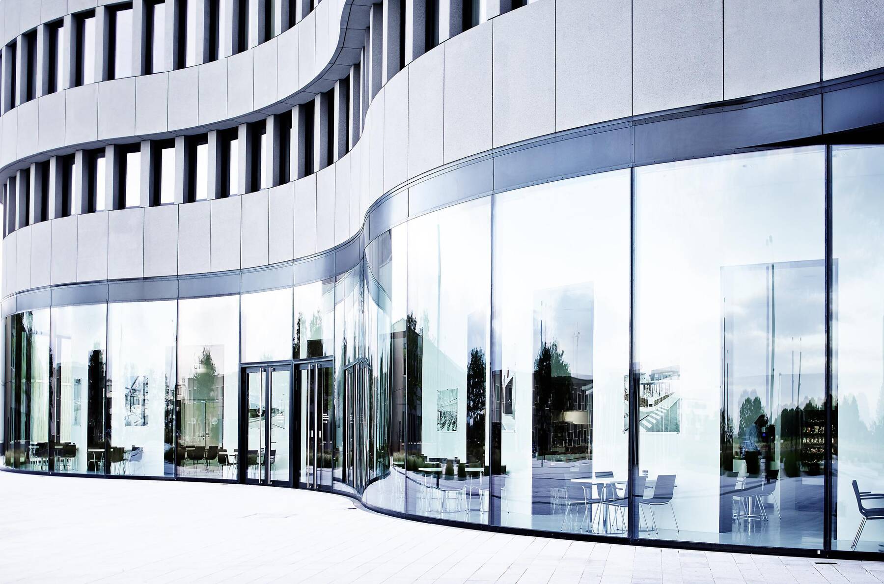 Exterior view of the circular Leica Camera building at Leitz-Park Wetzlar, featuring high-end TRALUX glass by Arnold Glas that mimics the look of high-quality camera lenses.